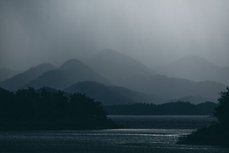 dark tone of mountain layers with lake  tropical forestの写真素材