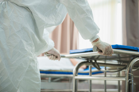 professional doctors in the full protective suits and surgical masks are examining the infected patient in the hospital control areaの写真素材