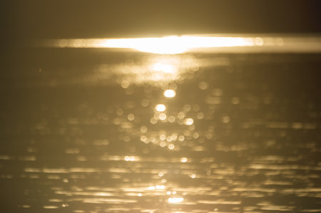 abstract blurry background if golden water surface at sunsetの写真素材
