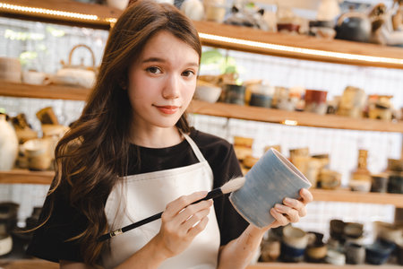 Beautiful young woman holding pottery instrument for scraping, smoothing, shaping and sculpting....