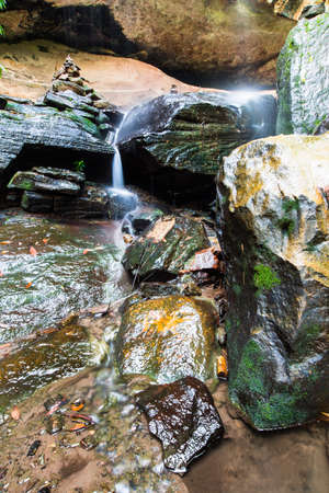 A beautiful forest waterfall and rocks between to the big cave.の写真素材