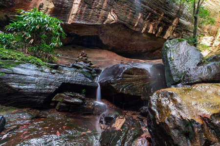A beautiful forest waterfall and rocks between to the big cave.の写真素材