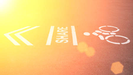 Sign on the cycling way meaning please share bike lanes for bikers.bicycles sign in the park with sunset light.の写真素材