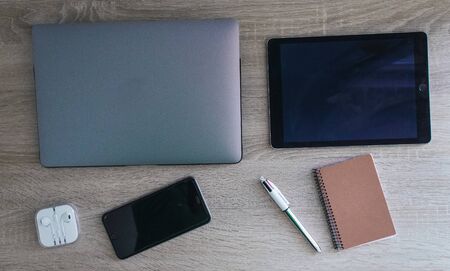 Gray computer with mobile devices notepad and pen on wood