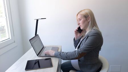 blonde girl calling on the phone and working at homeの写真素材