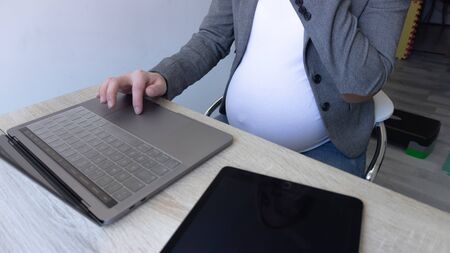pregnant girl with hands working on laptopの写真素材
