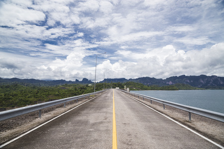 Road on the beautiful dam with cloud and blue sky