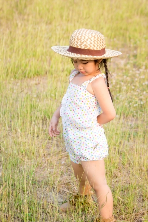 Little girl with sunhat in the fieldの写真素材
