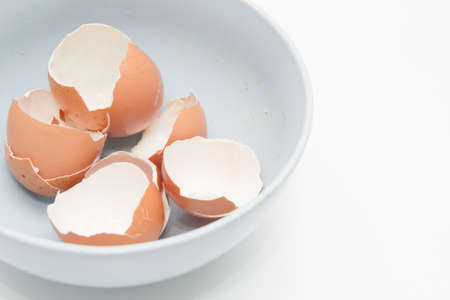 Heap of egg shell in a dirty bowl with white backgroundの写真素材
