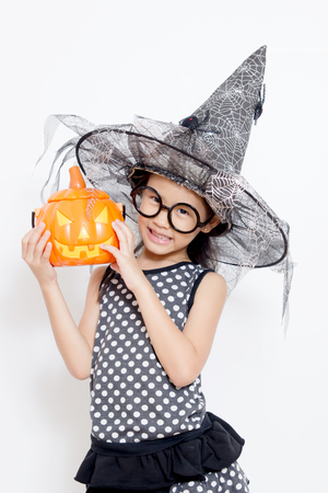 Happy witch child with pumpkin in Halloween dressの写真素材