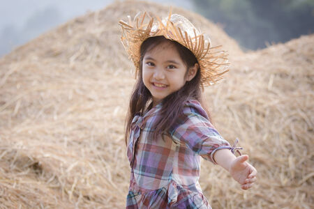Happy Asian child playing with straw stackの写真素材