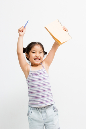 Happy Little Asian girl show her notebook and pencilの写真素材