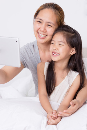 Little Asian child using tablet with motherの写真素材