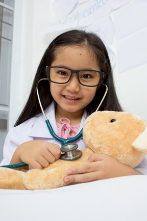 Asian girl playing as a doctor with stethoscope and bear dollの写真素材