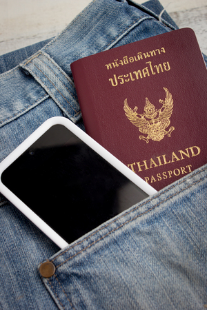 Thai passport in pocket of a jeans with smart phoneの写真素材
