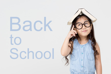 Portrait of little Asian child holding a book on head, Back to school concept の写真素材