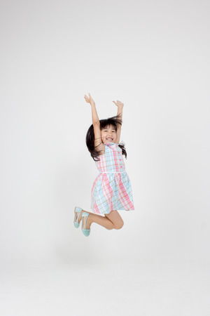 Portrait of happy little Asian child jumpingの写真素材