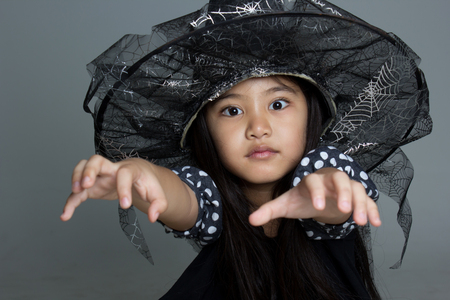Portrait of little Asian girl in black hat and black clothingの写真素材