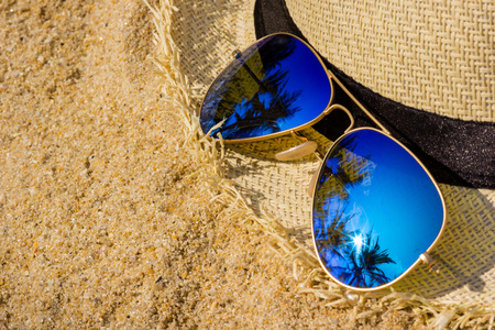 Sunglasses and sun hat on the sand beachの写真素材