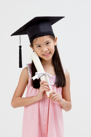 Happy Asian school kid graduate in graduation capの写真素材