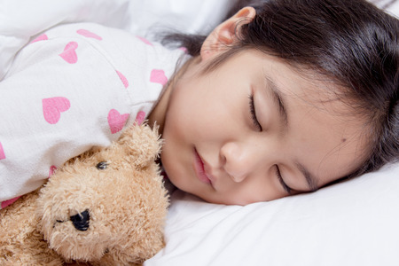 Lovely Asian child laying down on the bedの写真素材