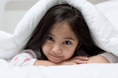 Lovely Asian child laying down on the bedの写真素材