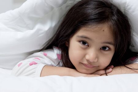 Lovely Asian child laying down on the bedの写真素材