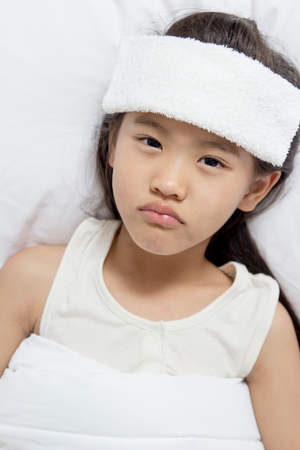 Little Asian child has fever and laying on the bedの写真素材