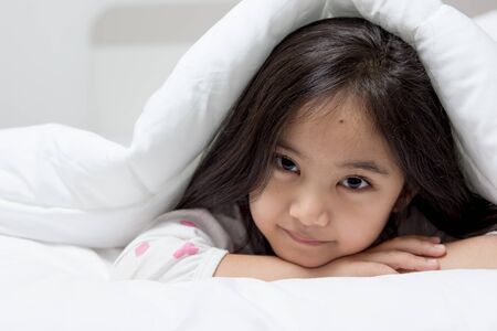 Lovely Asian child laying down on the bedの写真素材