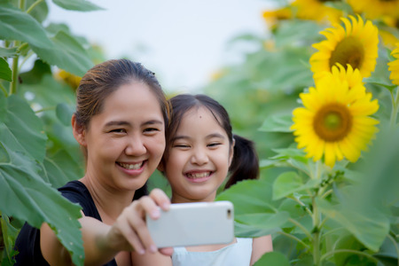 Asian mother and daughter taking selfie photograph togetherの写真素材