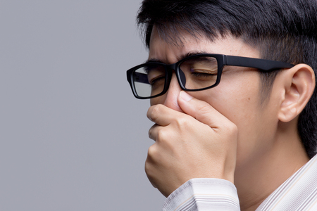 Portrait of Asian businessman sneezing on isolatedの写真素材