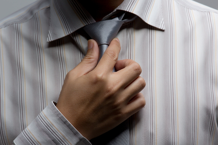 Asian business man shirt dressing up and adjusting tie on isolated