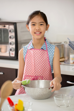 Little Asian cute chef cooking a bakery in kitchenの写真素材