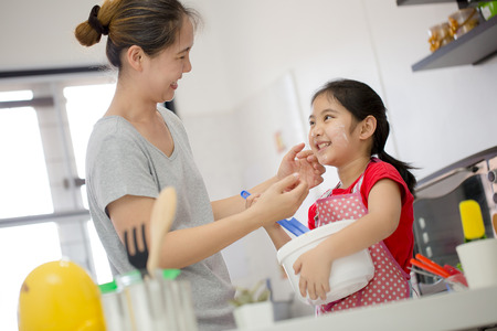 Little Asian cute chef cooking a bakery in kitchen with motherの写真素材