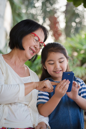 Little Asian girl touching smart phone with her grandmotherの写真素材
