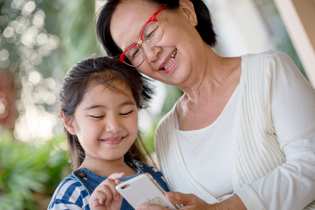 Little Asian girl touching smart phone with her grandmotherの写真素材