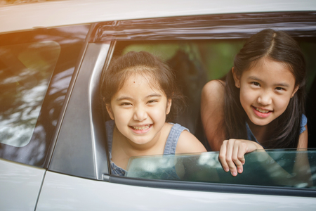 Happy Asian girl smiling on mini van window, Family traveling on summerの写真素材