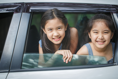 Happy Asian girl smiling on mini van window, Family traveling on summerの写真素材