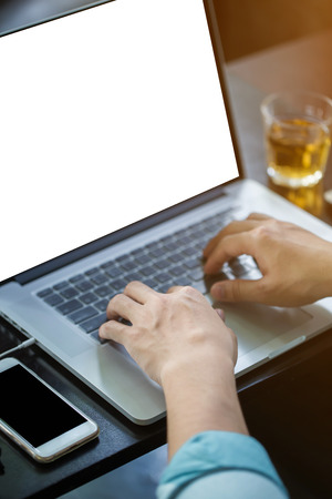 Hands of man using the laptop on a desk with white blank screenの写真素材