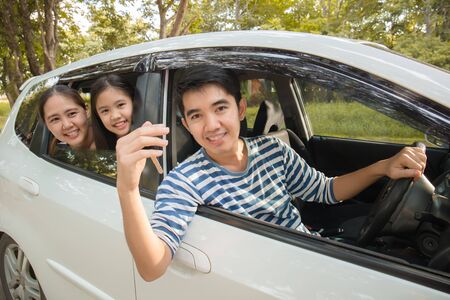 Happy Asian family on mini van are smiling and driving for travel on vacationの写真素材