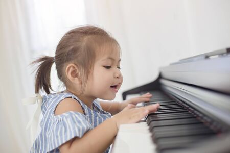 Happy little Asian girl playing piano at homeの写真素材