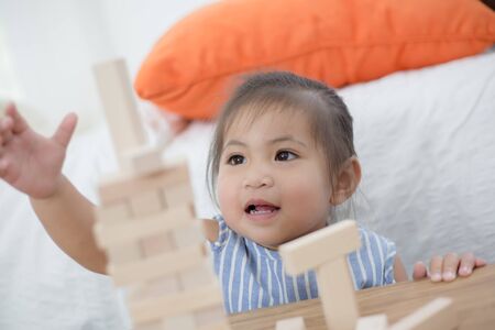 Portrait of happy little Asian girl playing with wooden blocksの写真素材