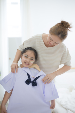Happy Asian mother helping daughter dressing her's uniform prepare to school, Back to schoolの写真素材