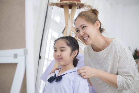 Happy Asian mother helping daughter dressing her's uniform prepare to school, Back to schoolの写真素材