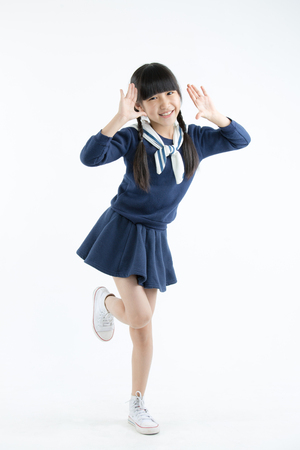 Happy long hair little Asian child smiling and dancing isolated on whiteの写真素材