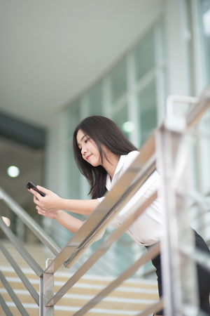 Young Asian woman executive working with a mobile phone in office buildingの写真素材