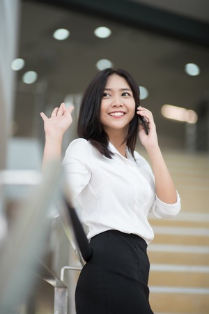 Young Asian woman executive working with a mobile phone in office building backgroundの写真素材