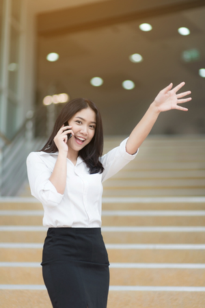 Young Asian woman executive working with a mobile phone in office building backgroundの写真素材