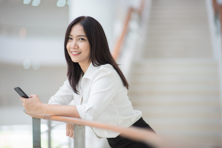 Young Asian woman executive working with a mobile phone in office buildingの写真素材