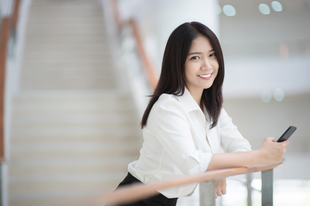Young Asian woman executive working with a mobile phone in office buildingの写真素材